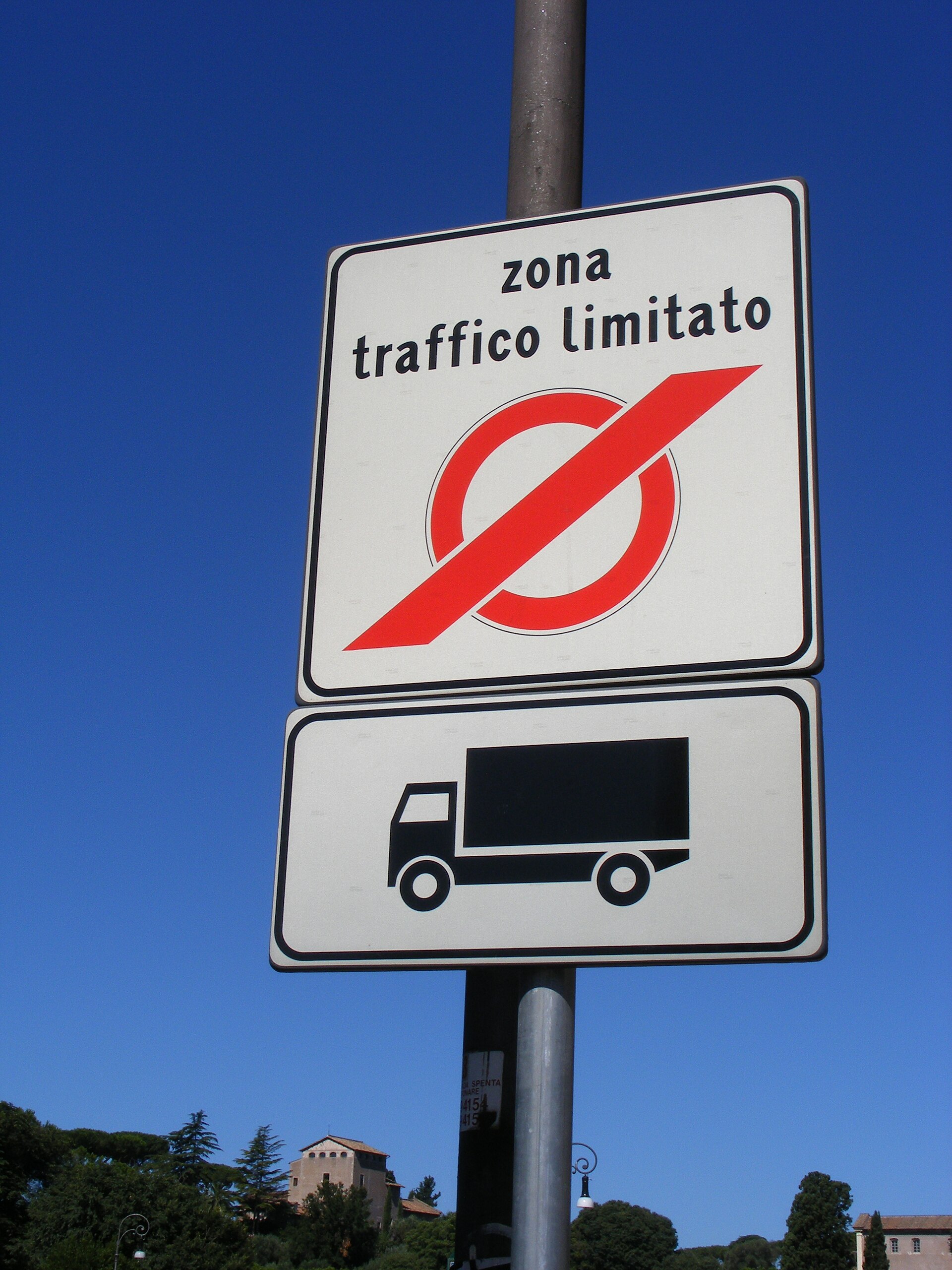 A ZTL boundary sign on a narrow street in central Italy — the red circle means cameras are active