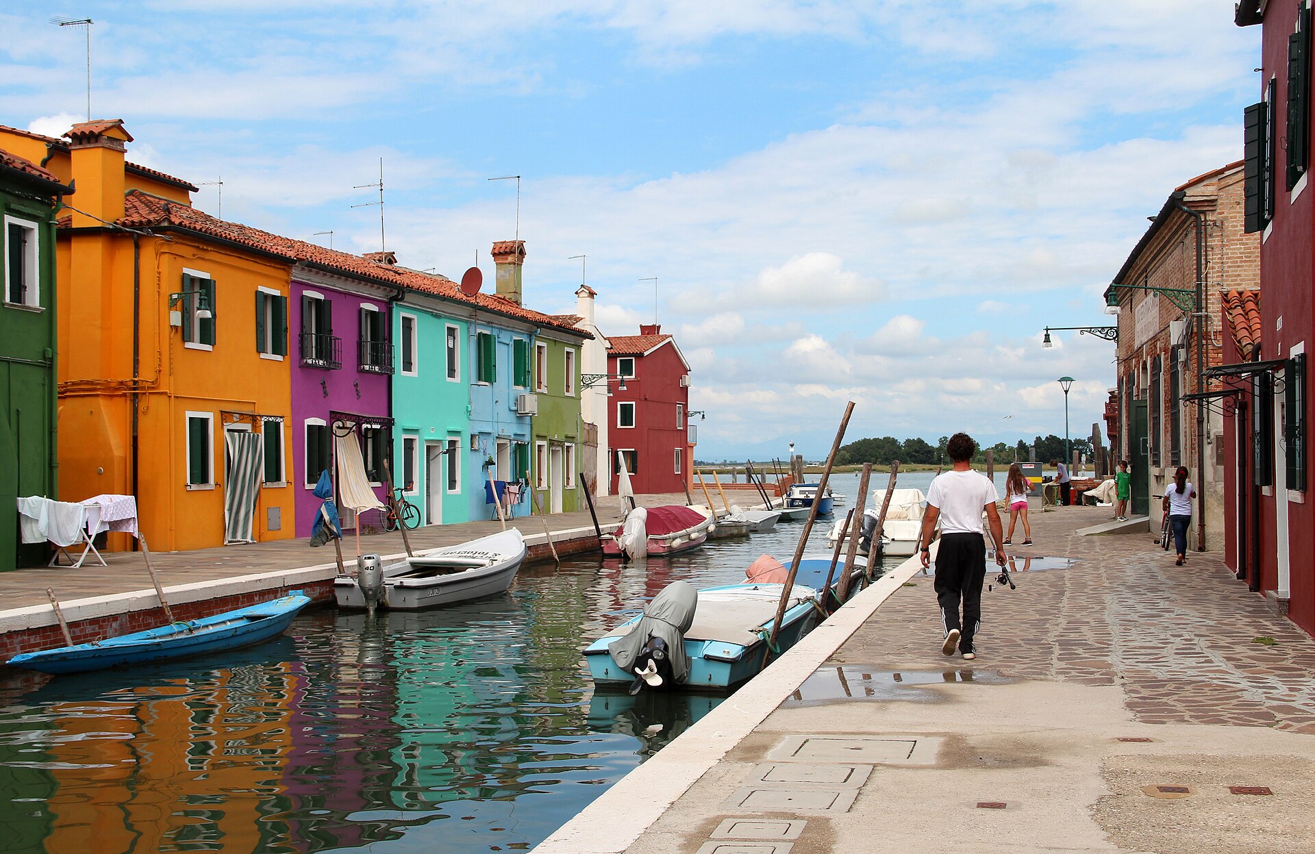 The painted houses of Burano reflected in the canal — the colours are assigned and regulated by the island's local authority